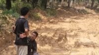 Terlihat warga melihat kondisi jalan yang rusak parah (